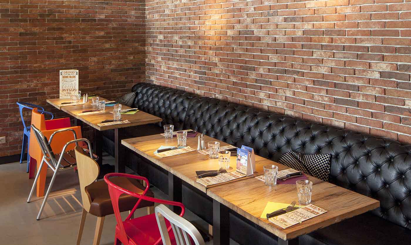 Banquette Chesterfield noire et tables du restaurant Popkfé